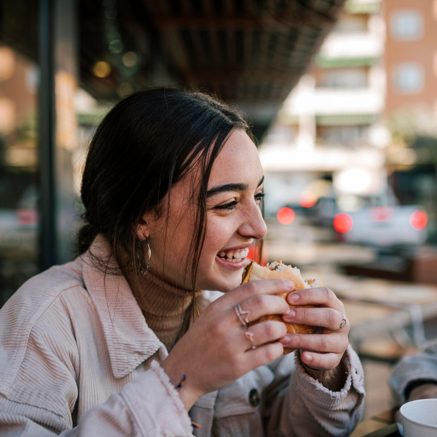 Gen Z women smiling while eating a hamburger