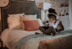 A kid enjoying screen time in bed