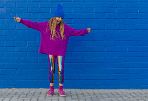 A girl dancing in front of a wall.