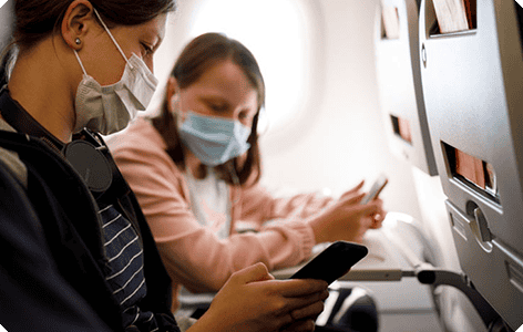 Two women on a plane sitting next to each other, wearing masks