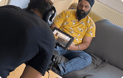 An India person wearing a turban and getting his podcast captured by another person