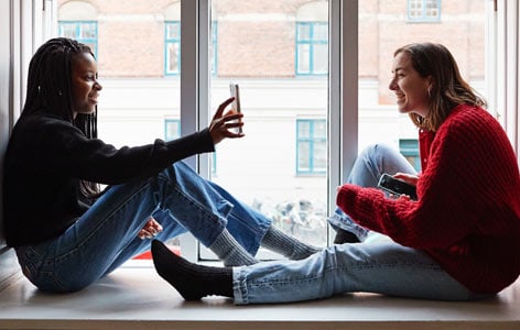 Two women siting and seeing a phone device
