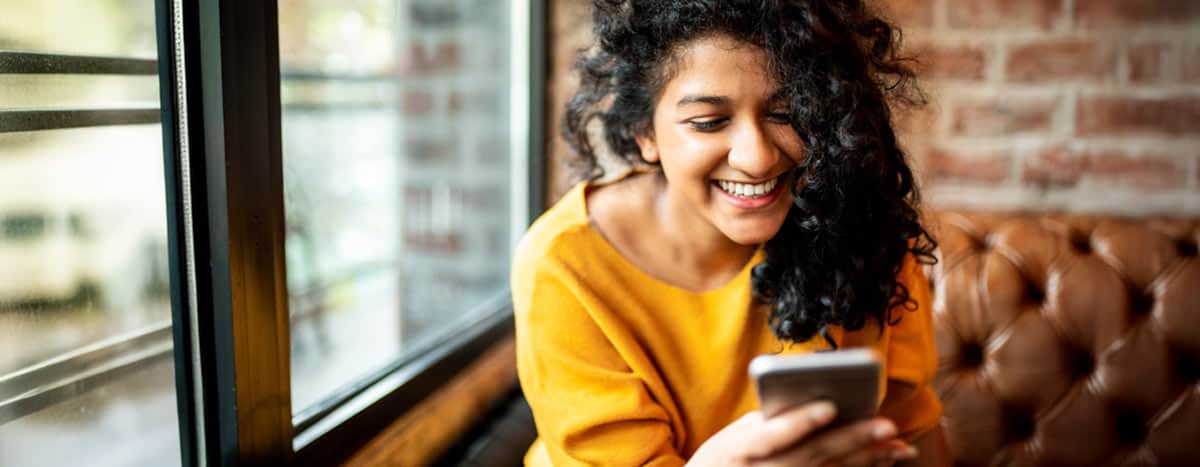 A women smiling and using her phone