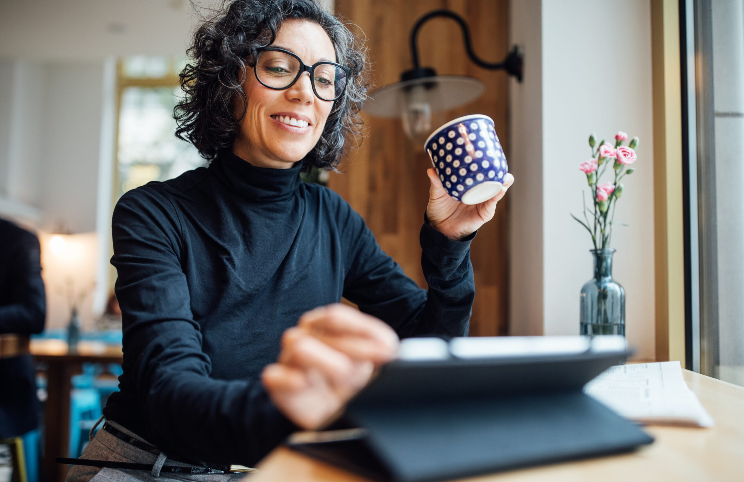 Smiling businesswomen sitting at a cafe and using a digital tablet