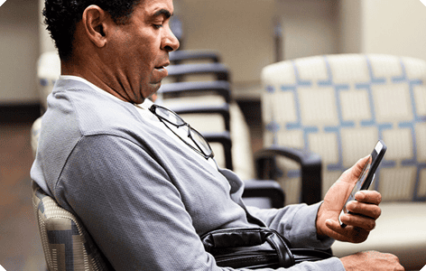 A man sitting on a wheelchair and using the phone