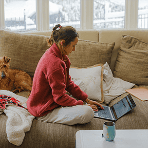 Woman on couch at home on computer