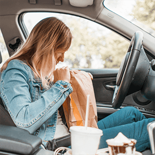Woman in car eating fast food