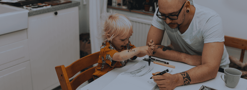 Father and young son coloring at the table