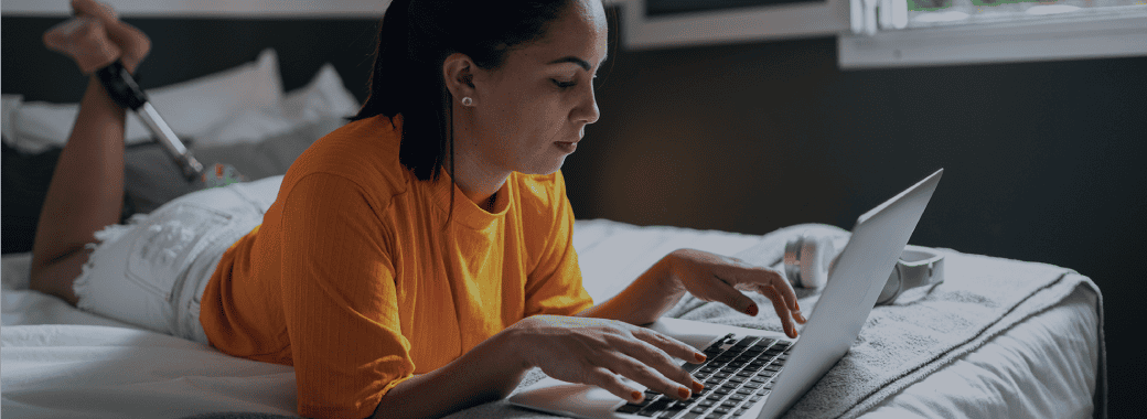 Woman working on laptop on bed