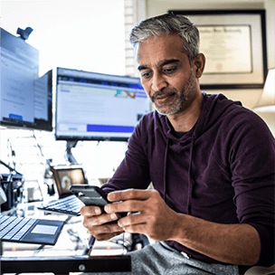 Man in home office looking at phone