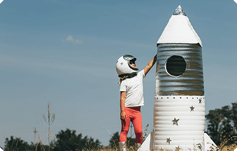 A kid standing next to a paper rocket