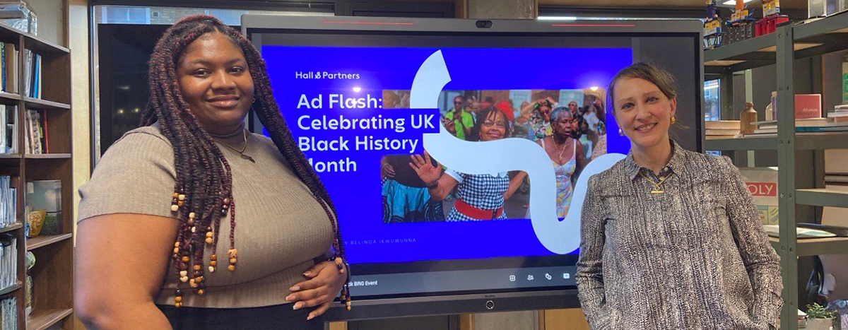 Two women standing in front of a screen displaying the Hall & Partners AD Flash