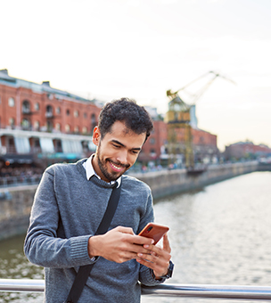 A man standing over a bridge and using his phone